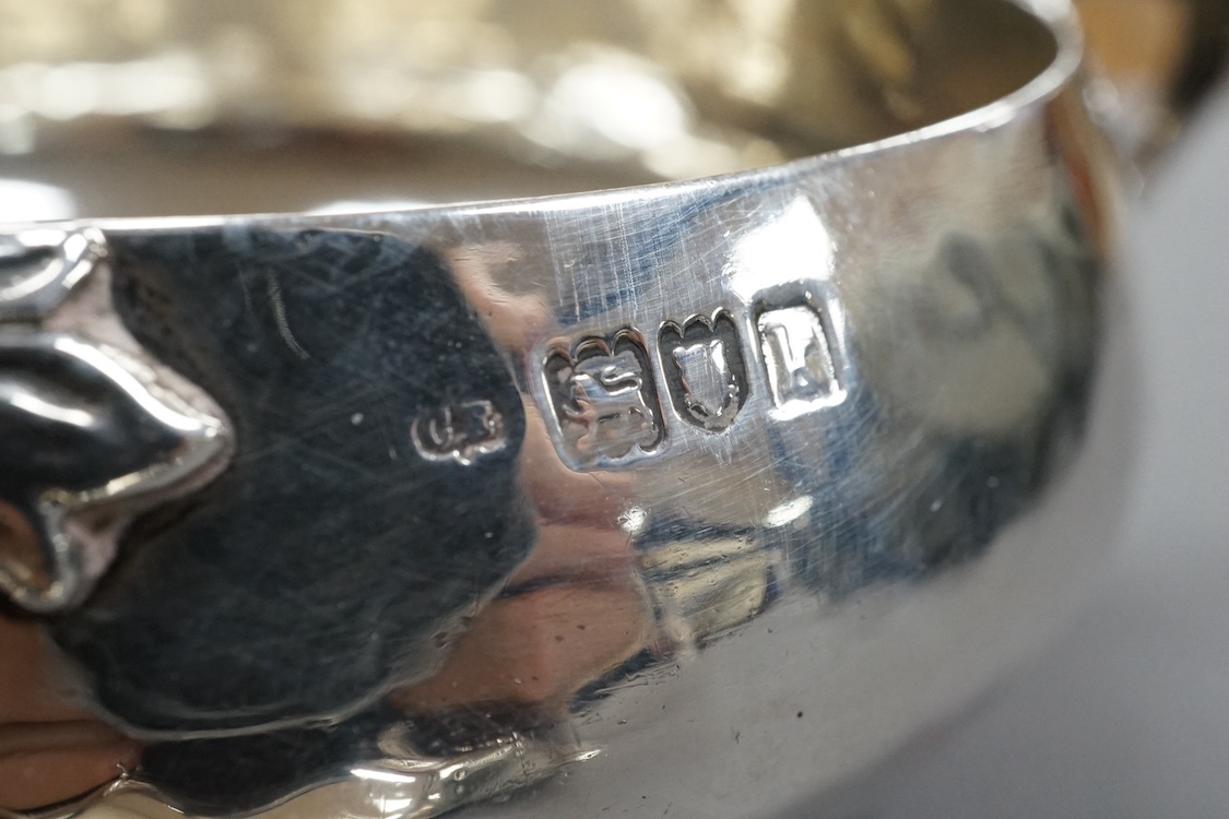 An Edwardian Art Nouveau planished silver tri-handled bowl by Charles Edwards, London, 1905, with stylised handles, diameter 94mm excluding handles, together with a pair of later silver two handled bonbon dishes, Deakin